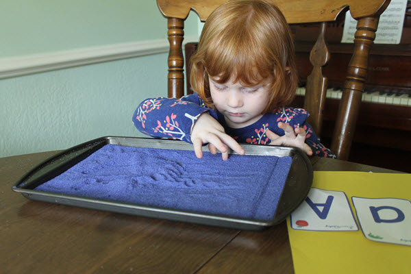Young child writing in a salt tray