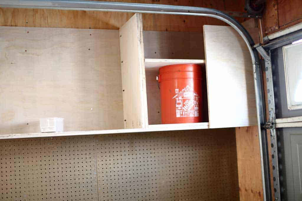 using a bucket as a guide to attach dividers of the garage cabinets