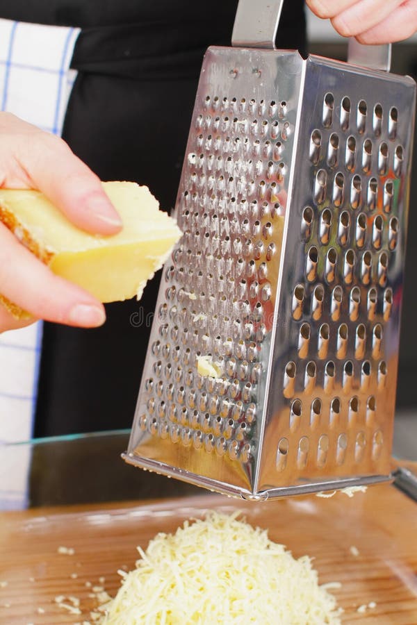 Cheese grater. Parmesan cheese with grater on wooden chopping board royalty free stock images