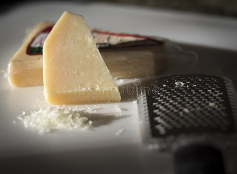 Cheese and Grater. White Cheese block and grater with grated cheese in front of cheese block. Italian food stock photo