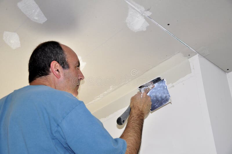 Drywall spackling. Man spackling drywall for a house renovation stock image