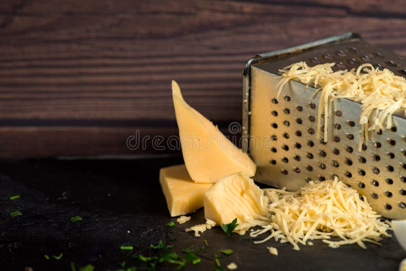 Grated cheese on a grater on a dark wooden background. close up.  royalty free stock images