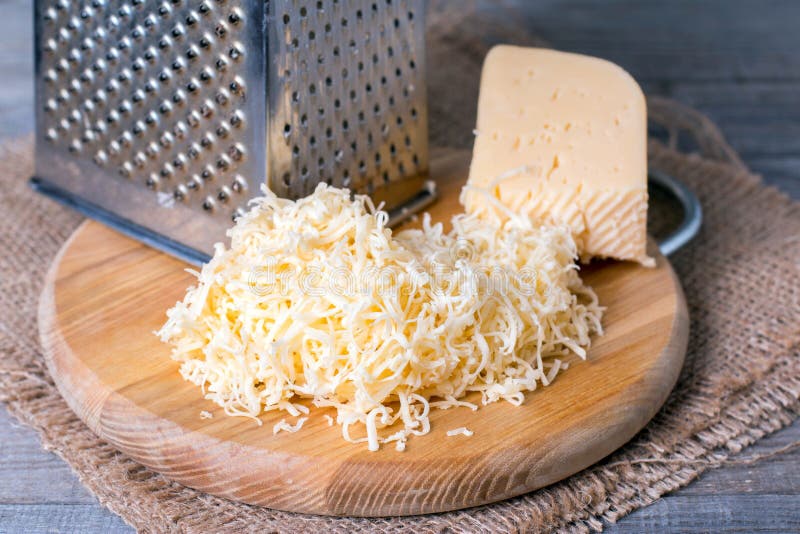 Grated cheese with grater. On a wooden background stock images