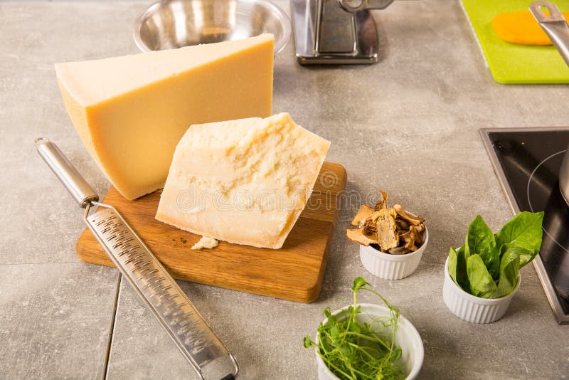 Grated parmesan cheese and metal grater on wooden board. With greens stock photography