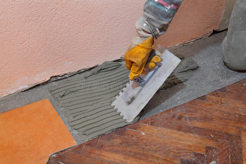 Home renovation, tiles. Home renovation, worker trowel spreading mortar for ceramic tile stock photo