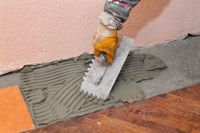 Home renovation, tiles. Home renovation, worker trowel spreading mortar for ceramic tile royalty free stock photo