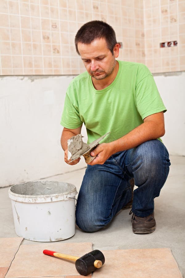 Man installs ceramic floor tiles - preparing the adhesive. Man installs ceramic floor tiles - preparing to apply the adhesive royalty free stock images