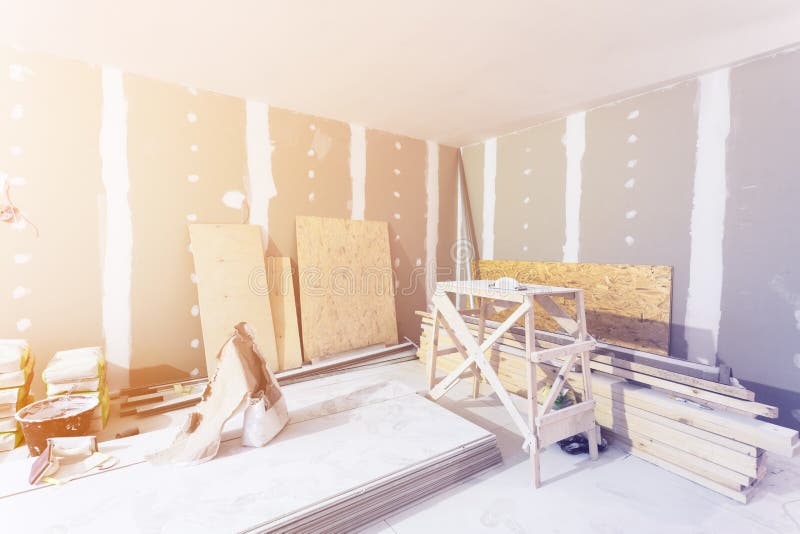 Materials for construction - putty packs, sheets of plasterboard or drywall- in apartment is under construction. Room interior and construction materials for stock photos