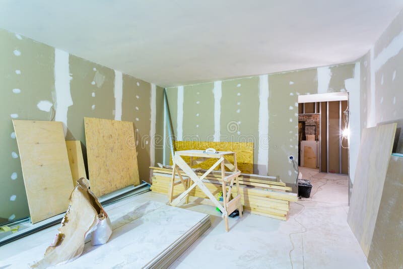 Materials for construction - putty packs, sheets of plasterboard or drywall- in apartment is under construction. Room interior and construction materials for stock image
