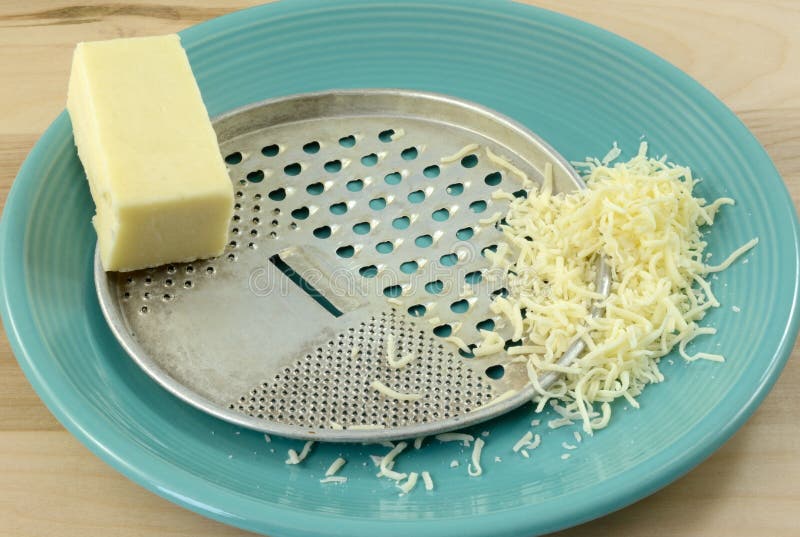 Retro vintage cheese grater with mozzarella cheese. Retro vintage cheese grater with block and shredded mozzarella cheese on blue plate stock photo