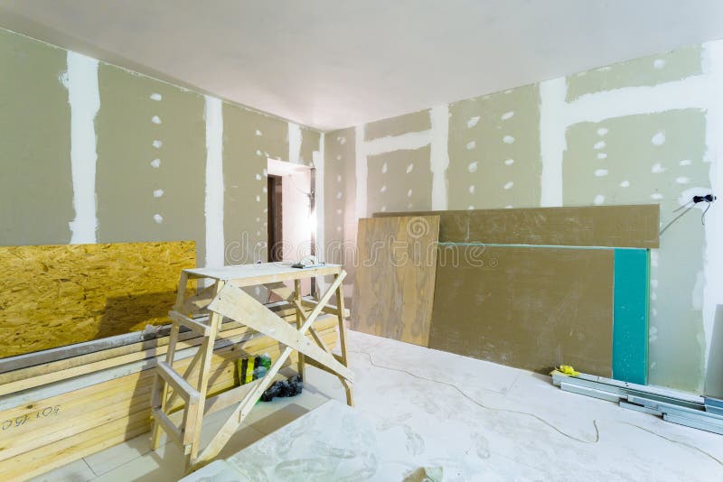 Materials for construction - putty packs, sheets of plasterboard or drywall- in apartment is under construction. Room interior and construction materials for stock images