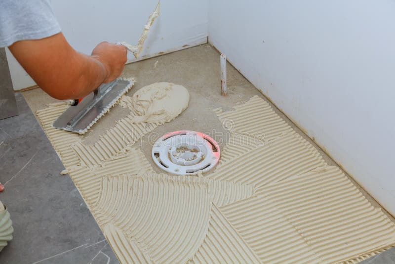Spreading wet mortar before applying tiles on bathroom floor royalty free stock photos