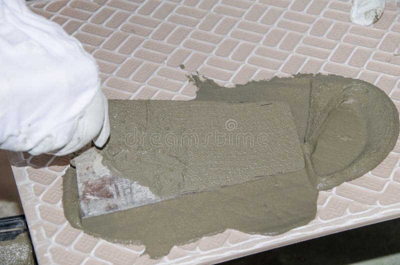 Tiler spreading tile adhesive on the back of a tile. Laying tiles, tiler spreading tile adhesive on the back of a tile royalty free stock images