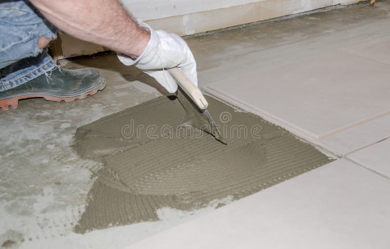 Tiler spreading tile adhesive on the floor. Laying tiles, tiler spreading tile adhesive on the floor stock photography