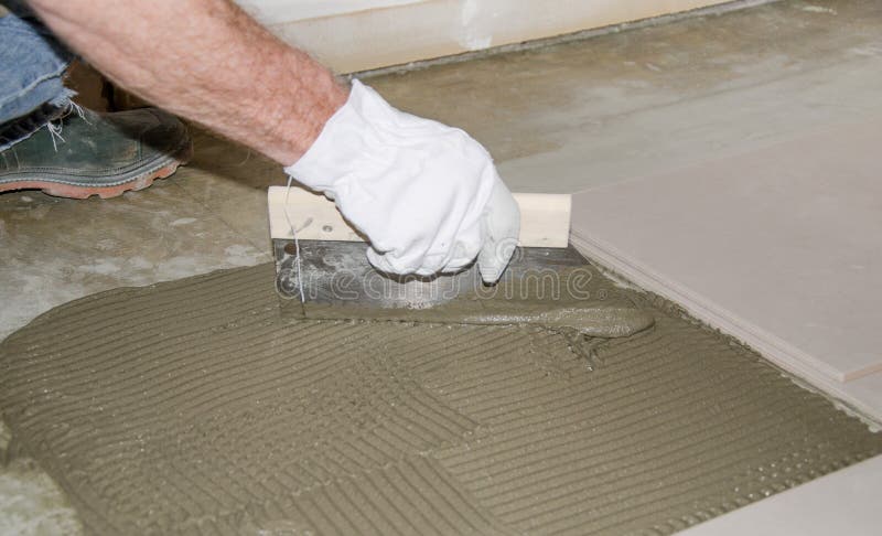 Tiler spreading tile adhesive on the floor. Laying tiles, tiler spreading tile adhesive on the floor royalty free stock photo