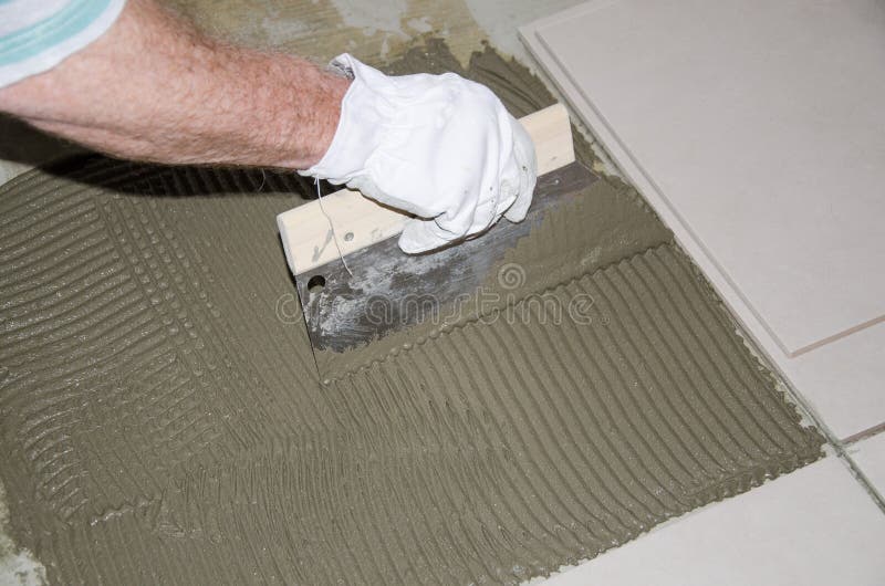 Tiler spreading tile adhesive on the floor. Laying tiles, tiler spreading tile adhesive on the floor stock image