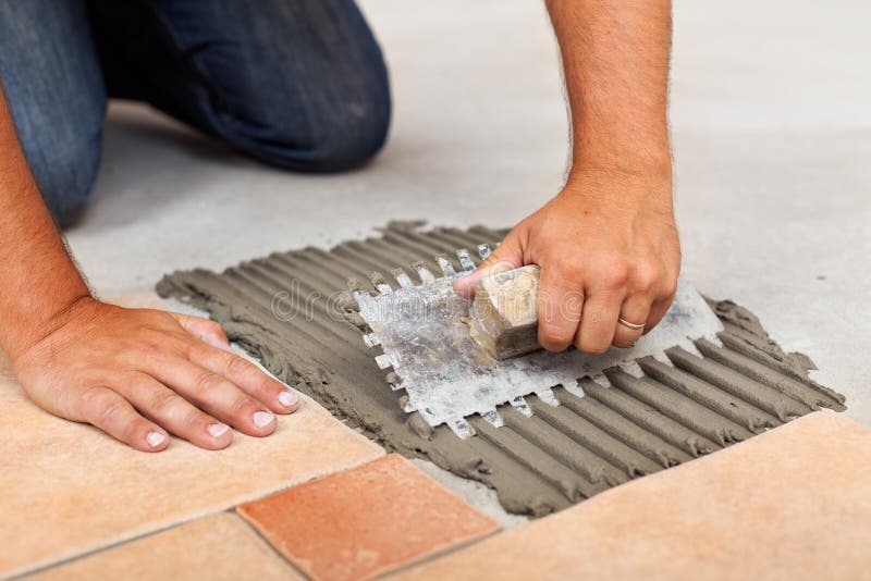 Worker hands spreading adhesive for ceramic floor tiles. Closeup stock photography