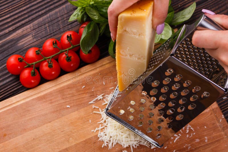 Young woman grater Parmesan cheese on a wooden board.  royalty free stock image