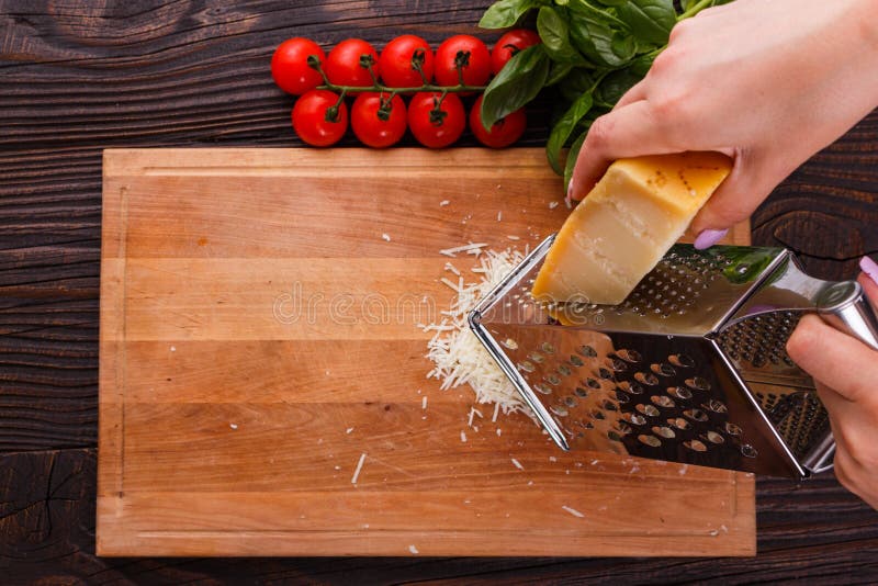 Young woman grater Parmesan cheese on a wooden board.  stock photos