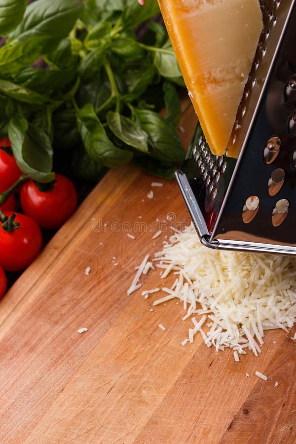 Young woman grater Parmesan cheese on a wooden board.  stock image