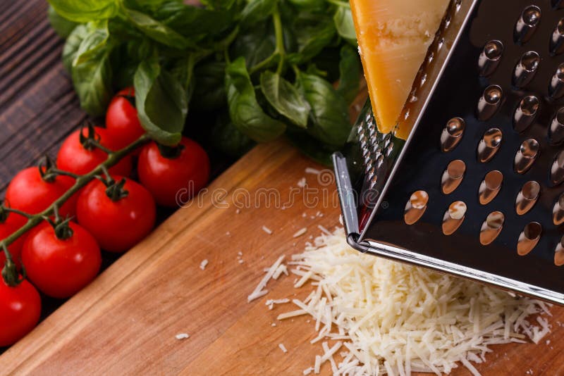 Young woman grater Parmesan cheese on a wooden board.  stock photos