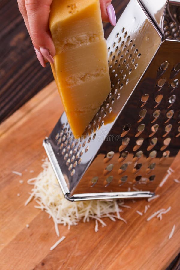 Young woman grater Parmesan cheese on a wooden board.  stock photography