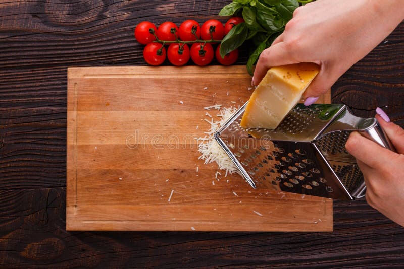 Young woman grater Parmesan cheese on a wooden board.  stock photos